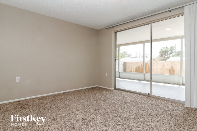 an empty living room with a large window and carpet