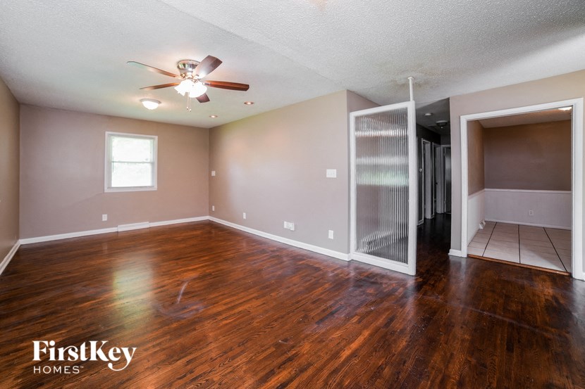 an empty living room with a ceiling fan and a closet