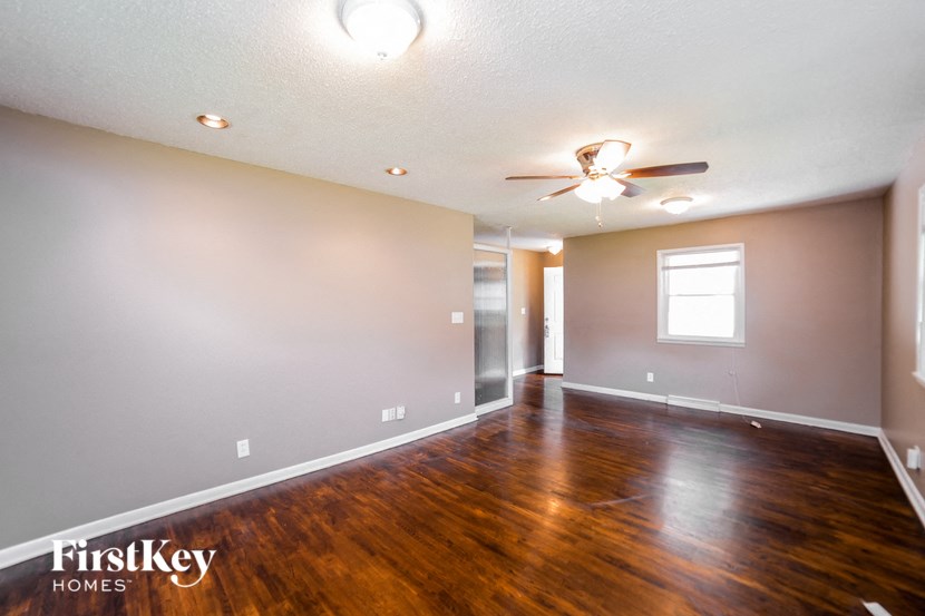 a empty living room with wood floors and a ceiling fan