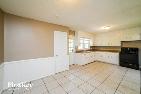 a large kitchen with white cabinets and tiled floors