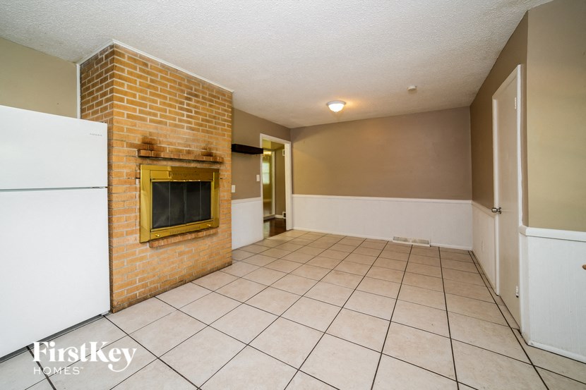a living room with a brick fireplace and a tile floor