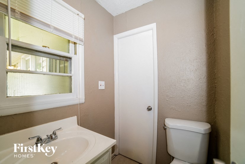a bathroom with a toilet and a sink and a window