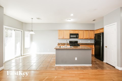 A kitchen with wooden cabinets and a black refrigerator.