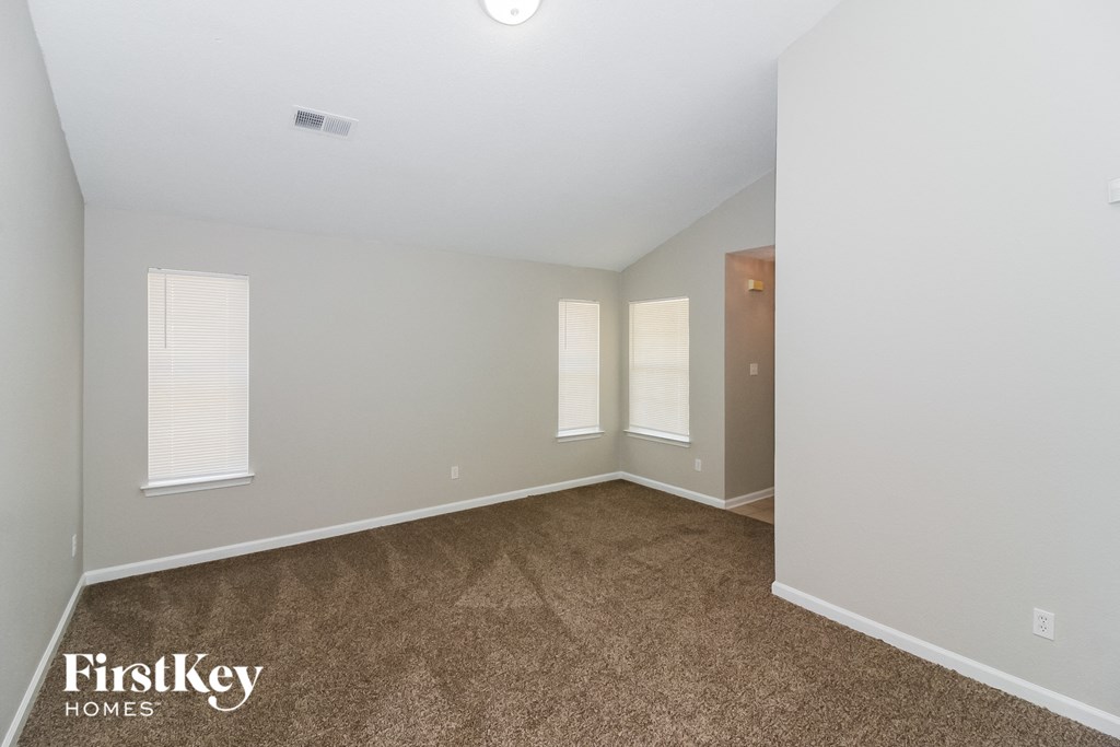 A room with a carpeted floor and a window with blinds.