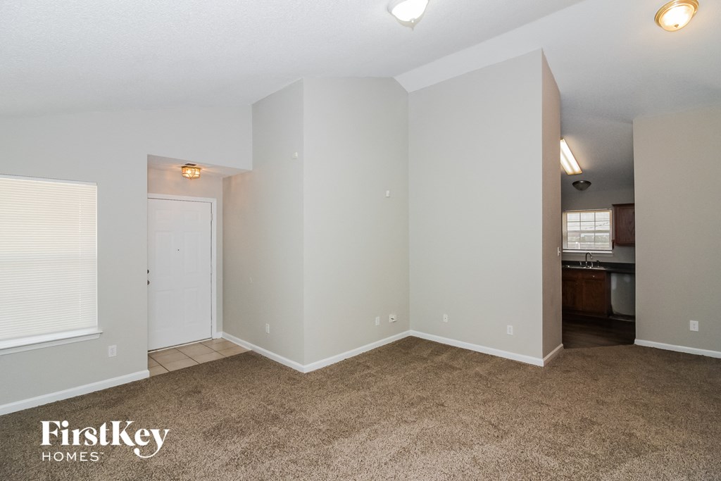 A room with a carpeted floor and a doorway leading to another room.