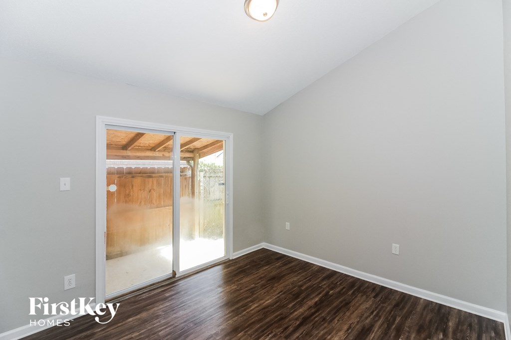 A room with wooden floors and a sliding glass door leading to a balcony.