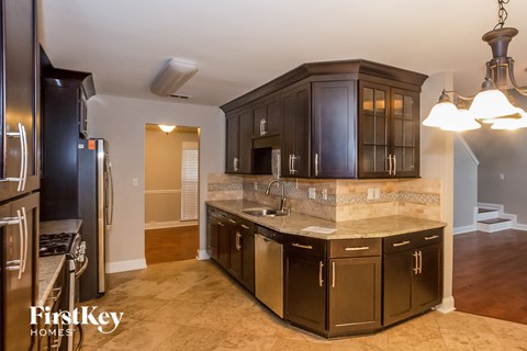 A kitchen with dark wood cabinets and a marble countertop.