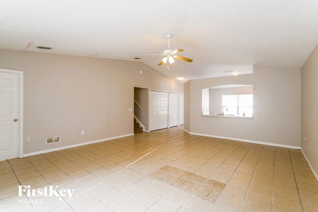 a empty living room with a ceiling fan and a tiled floor