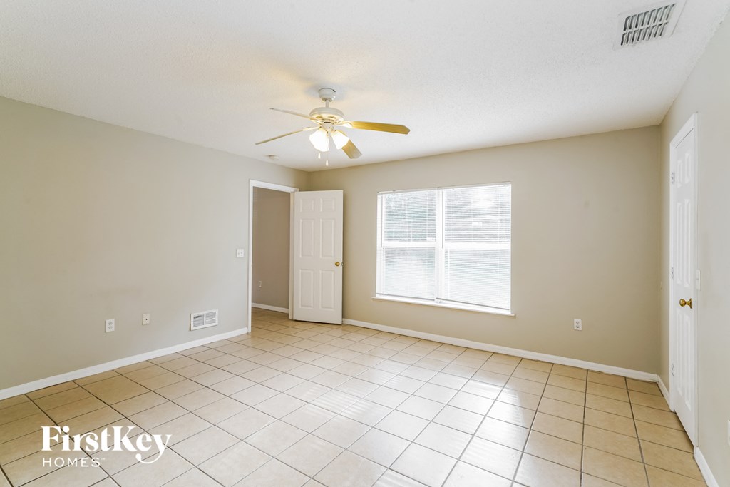 an empty living room with a ceiling fan and a window