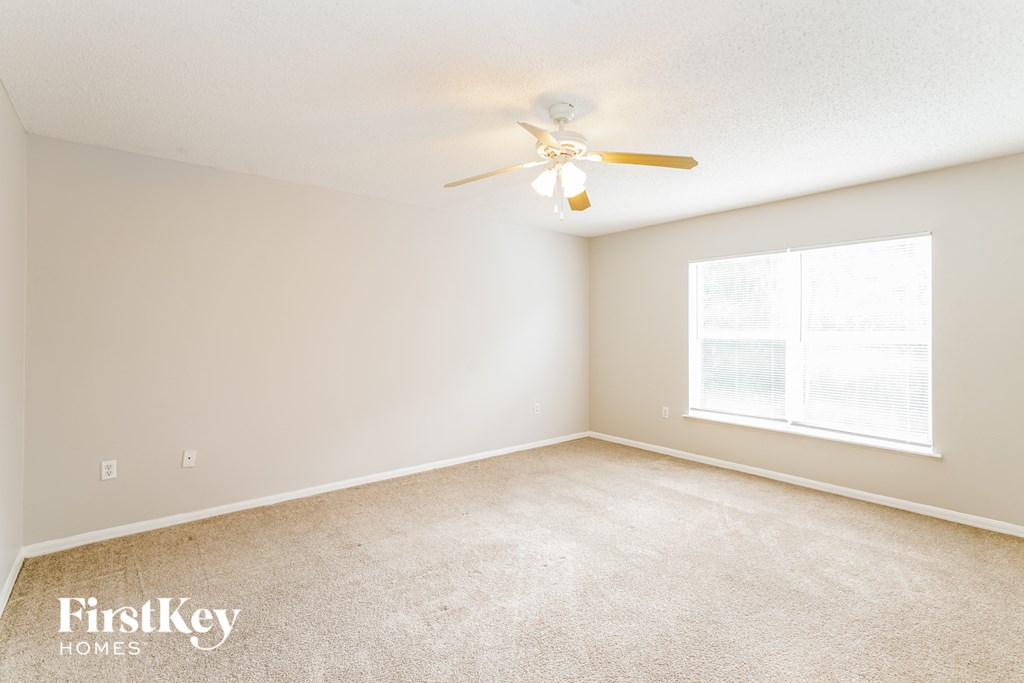 a bedroom with a ceiling fan and a large window
