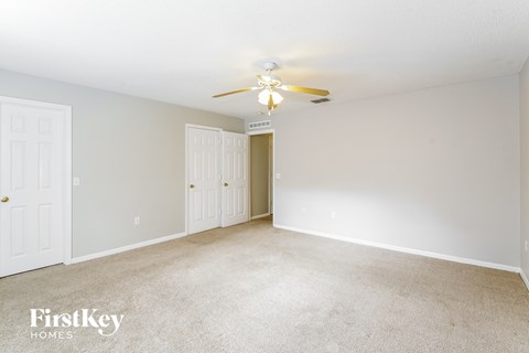a spacious living room with carpet and a ceiling fan