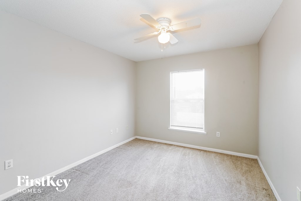 a bedroom with white walls and a ceiling fan and a window