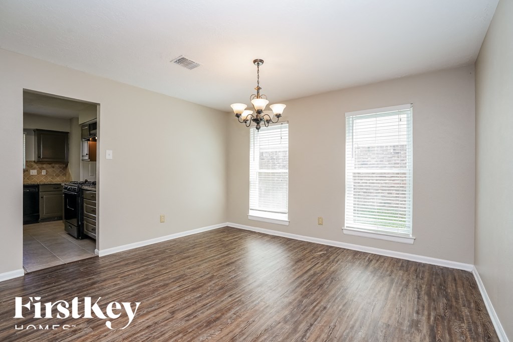 an empty living room with wood floors and a chandelier