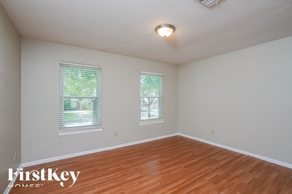 the spacious living room with hardwood flooring and two windows