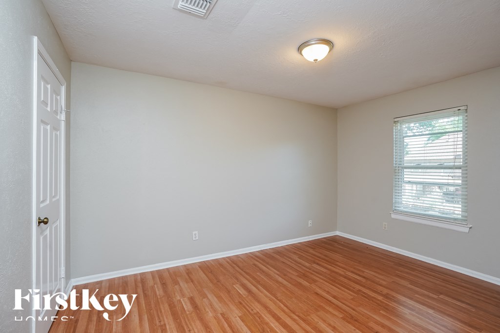 a bedroom with wood floors and white walls and a window