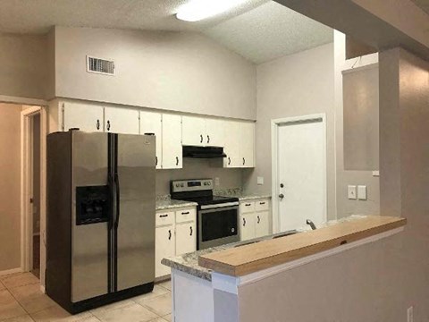 A kitchen with a refrigerator, oven, and cabinets.