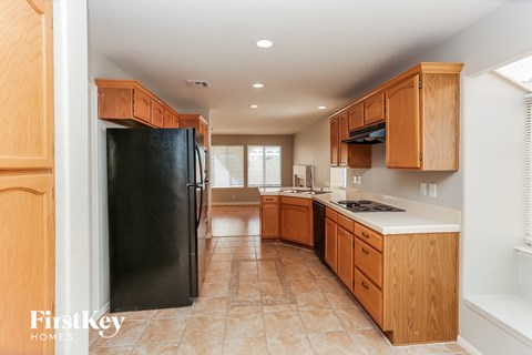 A kitchen with wooden cabinets and a black refrigerator.