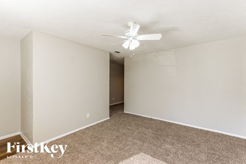 the spacious living room with carpeting and a ceiling fan