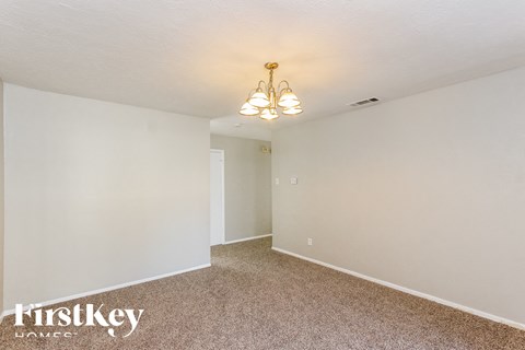 a bedroom with white walls and carpet and a chandelier