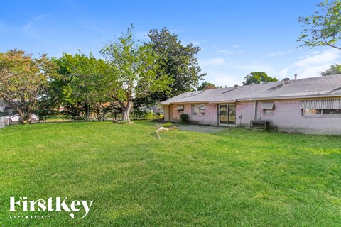 a backyard with a house and a deer in the grass