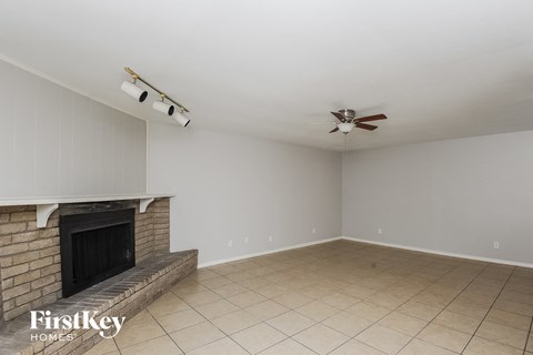 a living room with a brick fireplace and a ceiling fan
