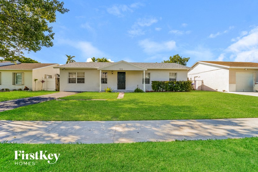 A white house with a green lawn in front of it.