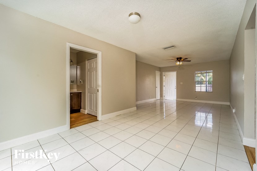 A spacious room with a ceiling fan and a doorway leading to another room.