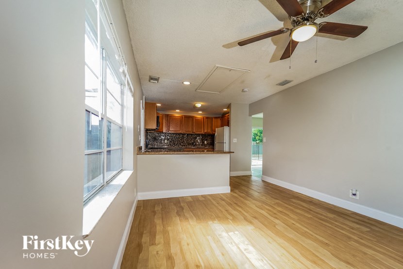 A spacious room with wooden floors and a ceiling fan.