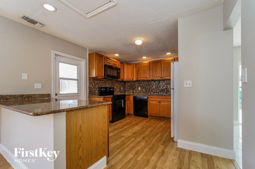 A kitchen with wooden cabinets and a black dishwasher.