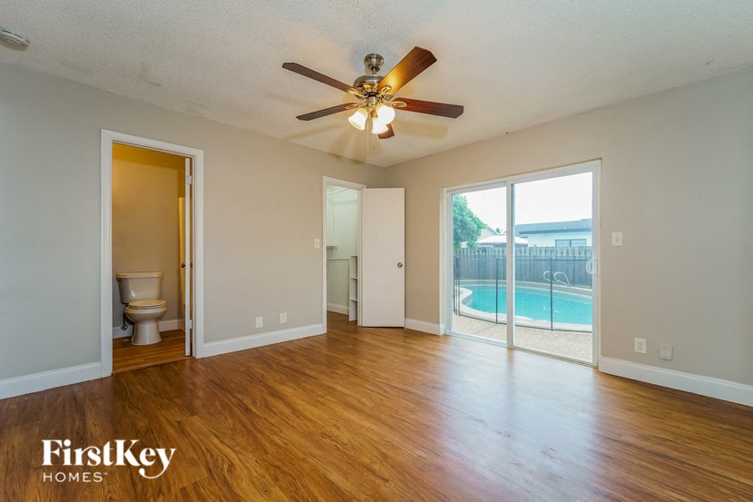 A room with a ceiling fan and sliding glass doors leading to a pool.