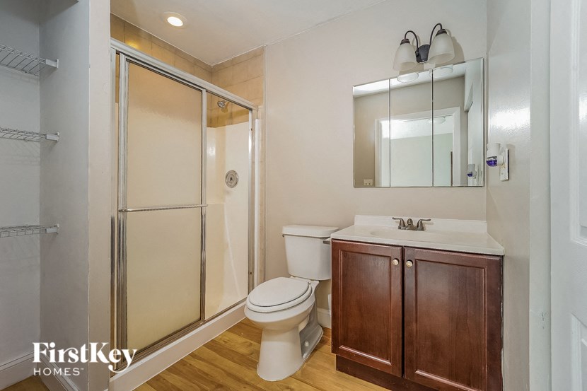 A bathroom with a toilet, sink, and mirror.