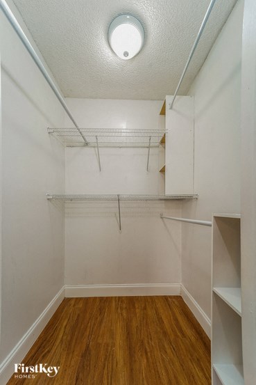 A small, empty room with a wooden floor and white walls.