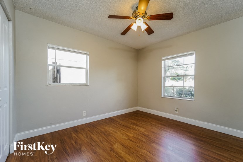 A room with a ceiling fan and two windows.