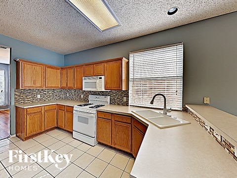 A kitchen with wooden cabinets and a white stove top oven.