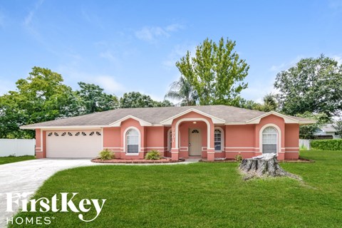 a pink house with a lawn and a driveway