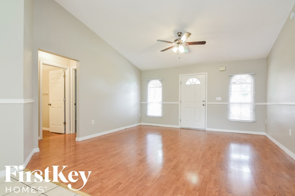 an empty living room with wood floors and a ceiling fan