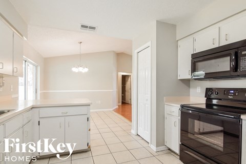 a large kitchen with white cabinets and black appliances