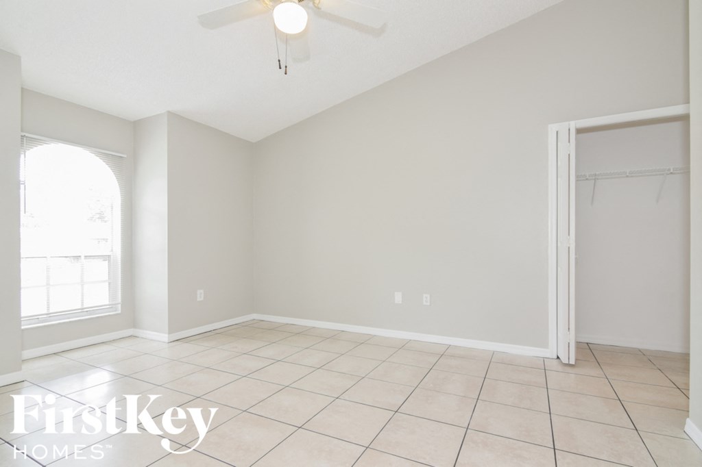 a empty living room with a ceiling fan and tiled floor