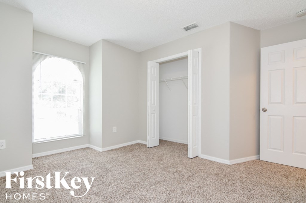 a bedroom with a closet and a window and a white door