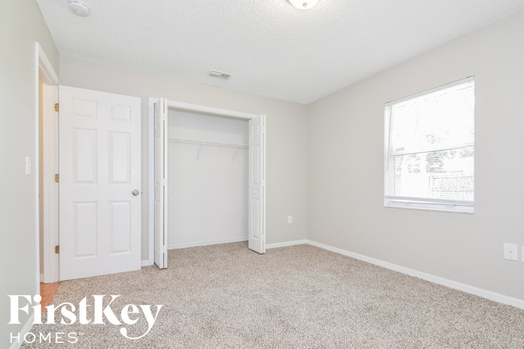 a bedroom with a door to a closet and a carpeted floor