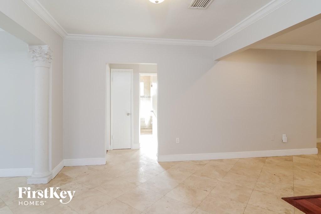 an empty living room with white walls and tiled floors