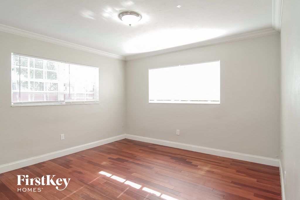 an empty room with wood flooring and two windows