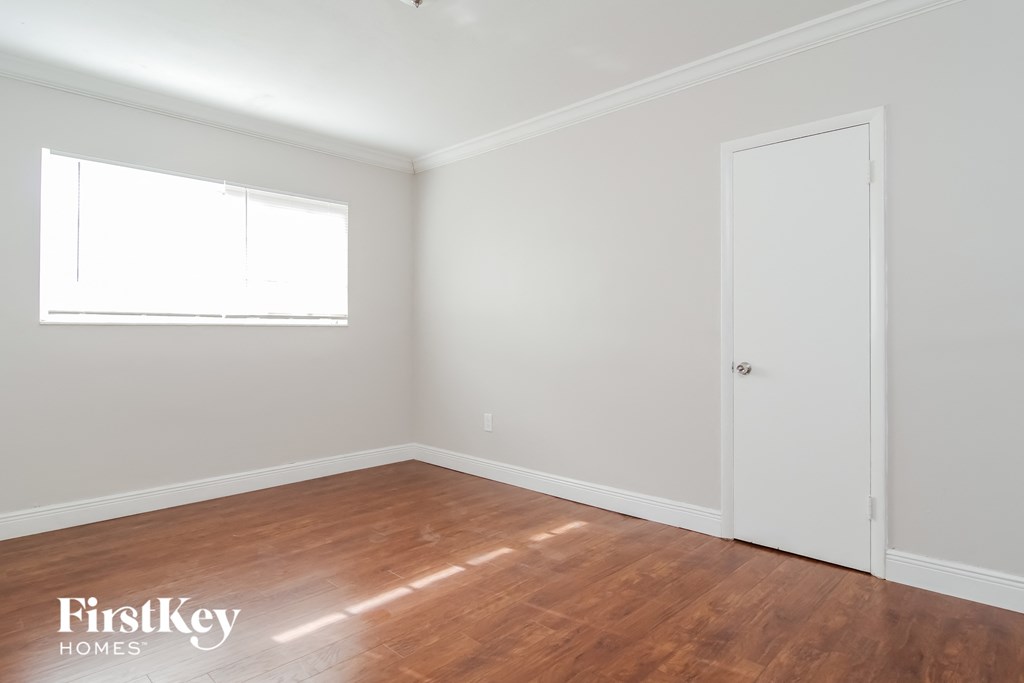 a bedroom with white walls and wood floors and a white door