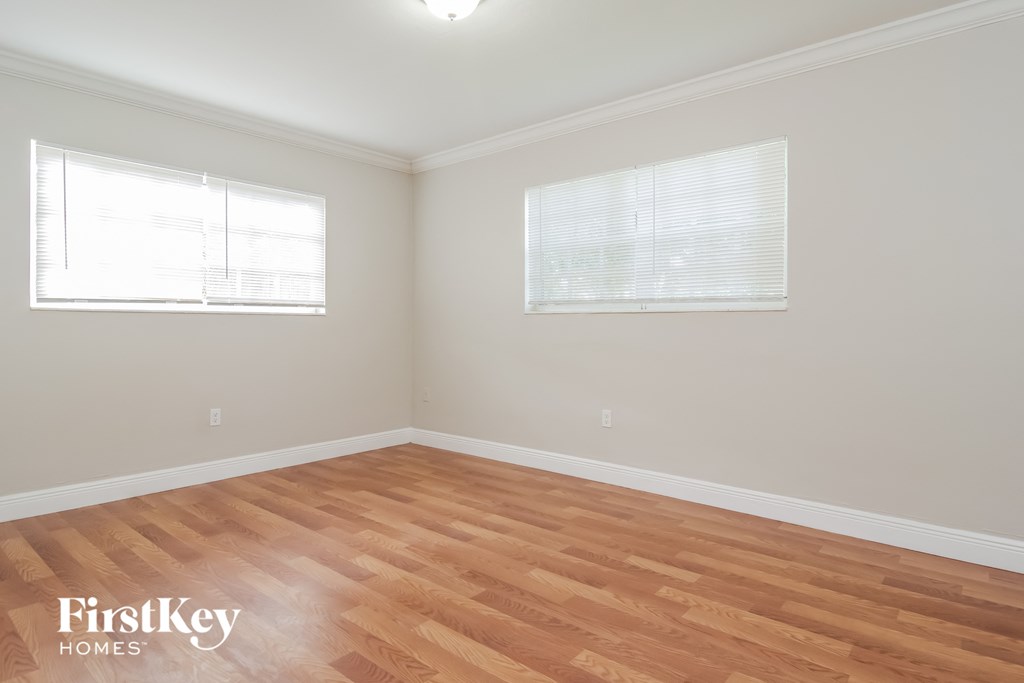 a living room with wood floors and two windows