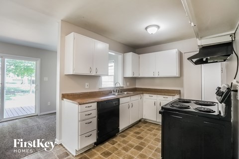 a kitchen with white cabinets and black appliances and a window