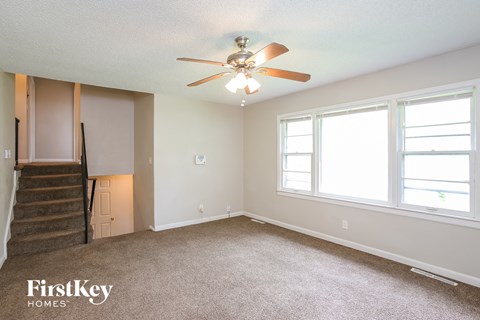 a living room with carpet and a ceiling fan