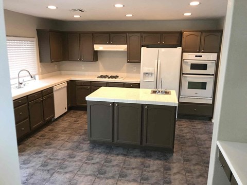 A kitchen with a white refrigerator and dark brown cabinets.