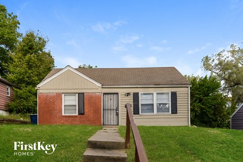 front view of a small brick house with a yard and stairs