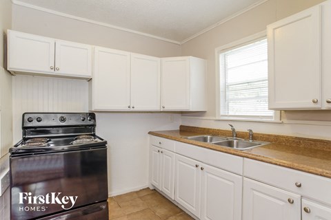 a kitchen with white cabinets and a stove and a sink