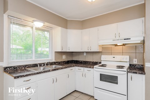A kitchen with white cabinets and a white stove top oven.